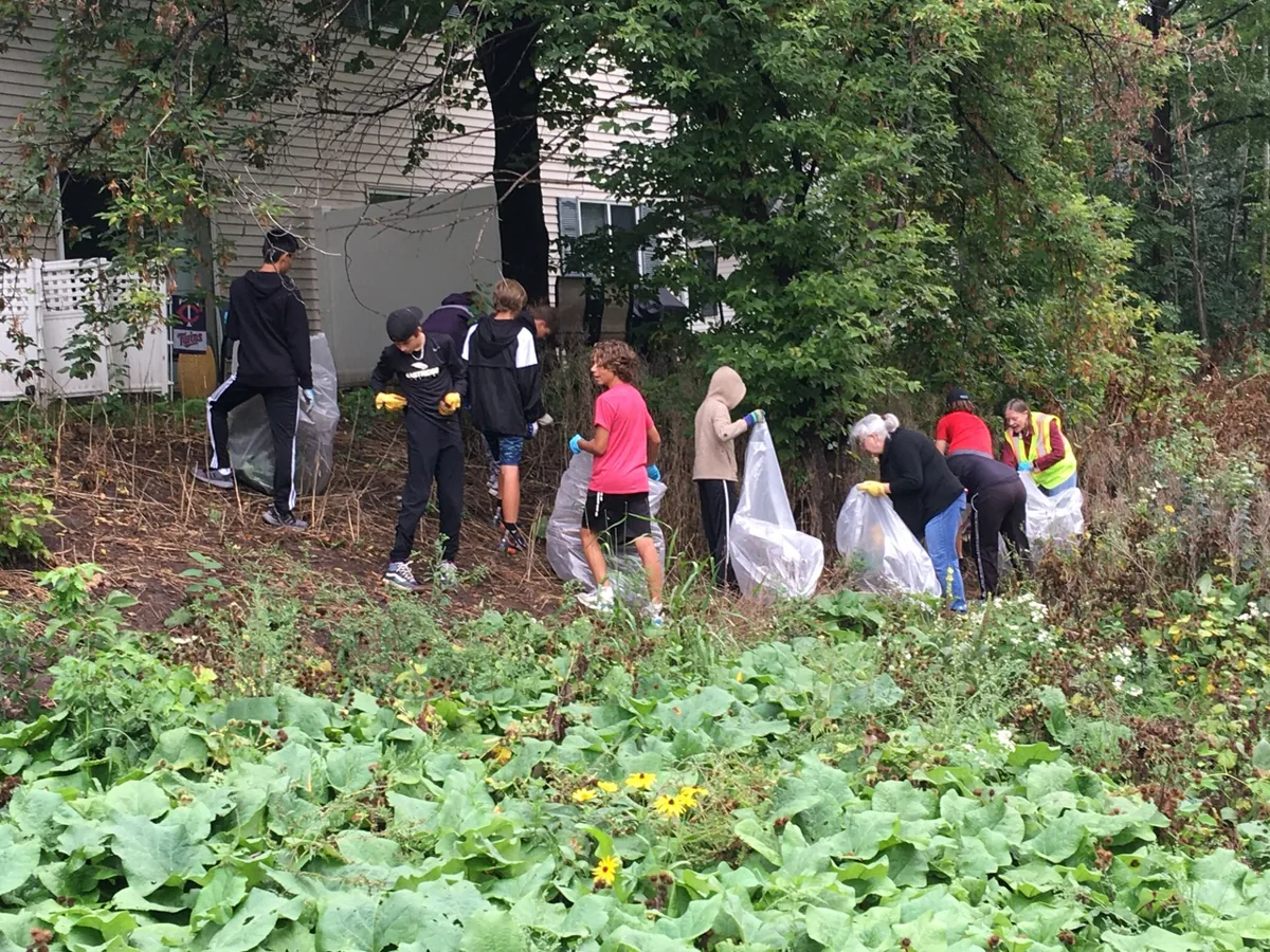 Volunteers spread out across a field for a Woodbury park clean-up